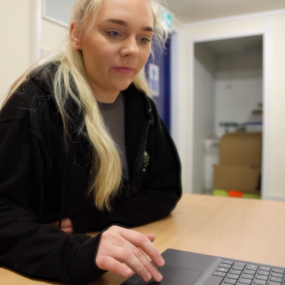 Benefits of fleet tracking shown by a Fleetview team member working on her computer to keep the clients updated.